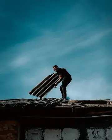 A roofer carrying materials across a roof